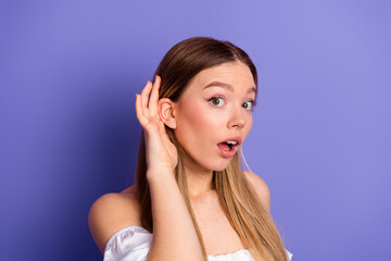 Lovely young woman in casual attire gestures towards ear on purple background ideal for promotions...