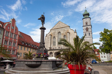 A wide-angle, low-angle view captures the iconic Lindavia Fountain in the marketplace of Lindau