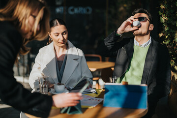 A group of colleagues discussing plans and ideas while enjoying beverages outside in natural light.