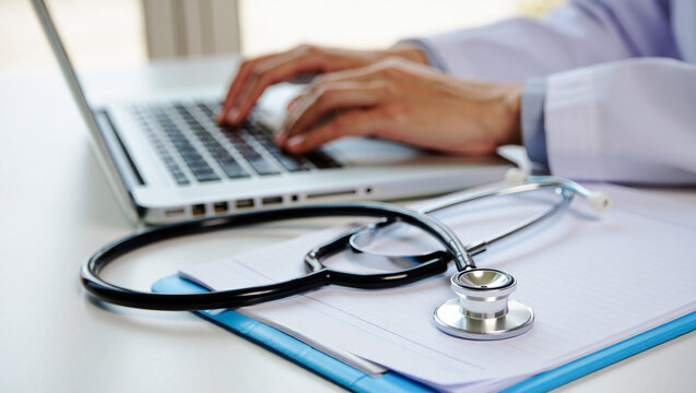 Doctor typing on laptop with stethoscope and medical chart image