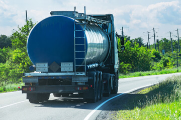 A fuel truck with a blue tanker drives along a country asphalt road