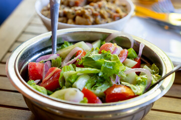 Cucumber and tomato salad with various herbs in a metal bowl