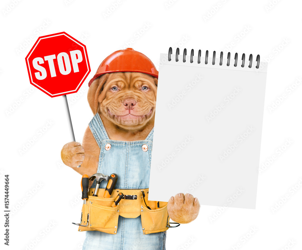Poster smiling mastiff puppy wearing helmet and overalls with tool belt shows stop sign and blank notepad. 