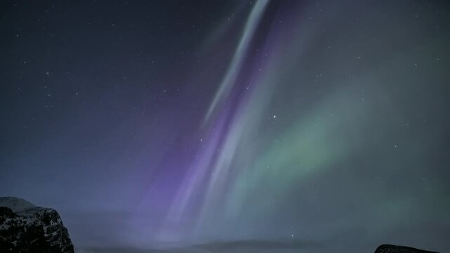 Auroras above snow-covered mountains, tilt down