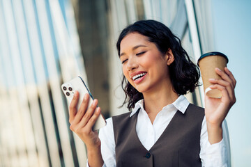 Confident professional woman enjoying a coffee break while engaging with her smartphone in a...