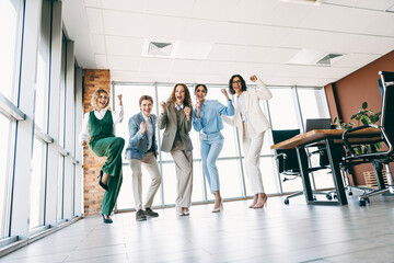 Fototapeta premium Joyful group of professionals celebrating teamwork success in a modern office space with bright and welcoming ambiance