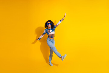 Stylish young woman enjoying leisure time against bright yellow background showcasing fashion and...