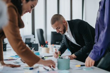 Group of diverse professionals engaging in teamwork and brainstorming during an office workshop.