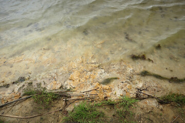 The clay and sandy bottom of the lake is clearly visible through the clear, transparent water.