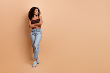 Young fashionable woman posing confidently on beige background in casual attire and brown top with...