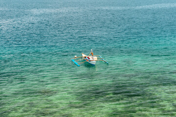 Golden Hour with Anchored Bangkas boat in blue water coral reef Sea in the Philippines