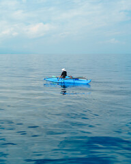 Scenic shot of man kayaking in blue boat in calm turquoise waters in Moalboal, Cebu, Philippines