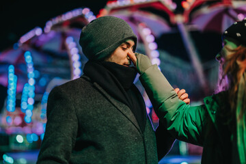 A cheerful outdoor scene of a couple sharing a playful moment under colorful festival lights.