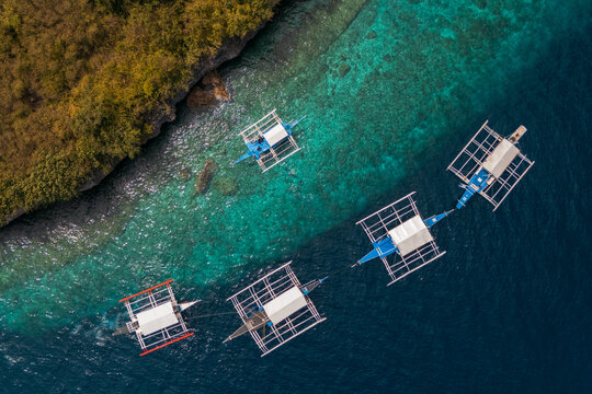 Top view bird's eye of Cluster of Bangkas boats Anchored Along the Vibrant Reefline and turquoise waters of Pescador Island &ndash; Moalboal, Cebu, Philippines