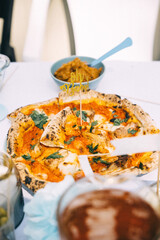 Delicious pizza topped with herbs and accompanied by side dishes at a dining table