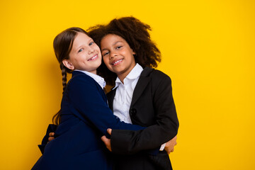 Diverse schoolgirls smiling together in uniforms against yellow background celebrating friendship and unity