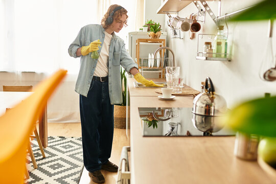 Handsome young man cleaning his stylish kitchen while enjoying time at home during the day