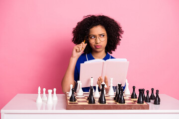 Smart young Woman in Stylish Casual Clothing Playing Chess and Contemplating Strategy on a Pink...