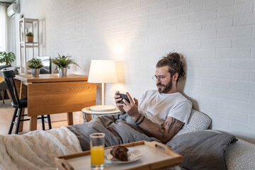 Freelancer playing videogames in bed on a lazy morning