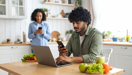 Couple using devices with kitchen.