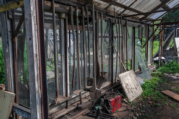 Old tools hanging in a rustic greenhouse create a serene rural scene.
