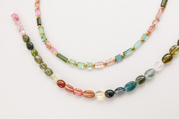 Colorful Tourmaline Beads in Mixed Shapes and Shades on a Light Background

