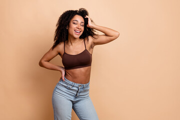Confident young woman in casual fashion standing against a beige background enjoying leisure with a...