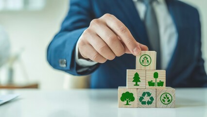Businessman builds a tower of wood blocks with green ecology concept icons