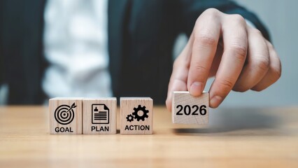 Business strategy shown with wood blocks displaying goal, plan, action and 2026