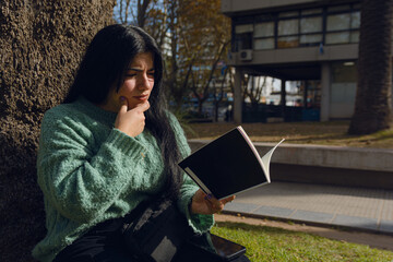 young confused woman reading a book in the park