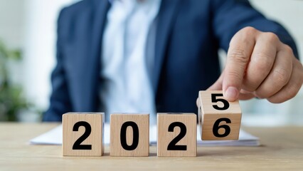 Person forming the year 2026 with wooden blocks on a table