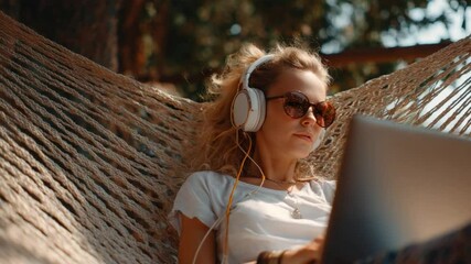 Serene Hammock Escape: A woman enjoying leisurely time outdoors, immersed in music and a laptop, suspended in a hammock strung between trees, bathed in warm sunlight.