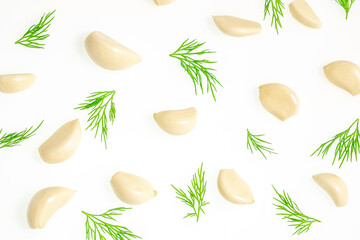 Fresh garlic cloves and green dill leaves scattered on a white background, ideal for cooking,...