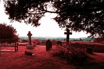 A strange infrared like vaporwave edit. Gravestones in a cemetery, in the countryside on a summers...