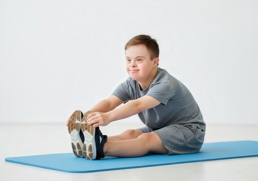 Young boy with Down syndrome smiling while stretching on exercise mat in gym