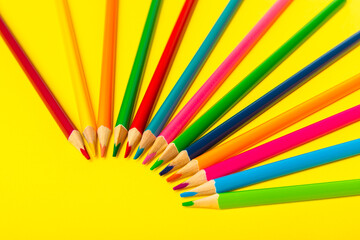 Colored pencils on a bright colored background. Equipment for coloring. Stationery for...