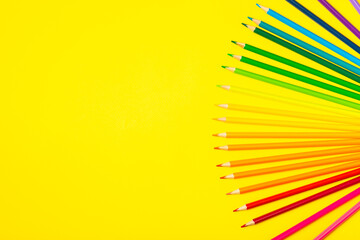 Colored pencils on a bright colored background. Equipment for coloring. Stationery for...