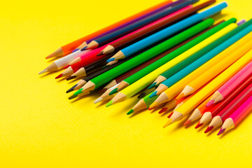 Colored pencils on a bright colored background. Equipment for coloring. Stationery for...
