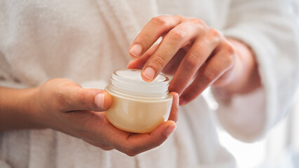 Woman holding jar of moisturizing cream