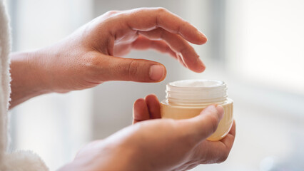Woman holding jar of moisturizing cream