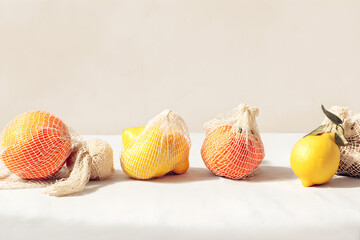 Fresh Fruits in Mesh Bags on Light Surface