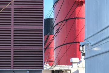 Red and black funnel of historic oceanliner ocean liner Mary against deep blue sky with clouds	