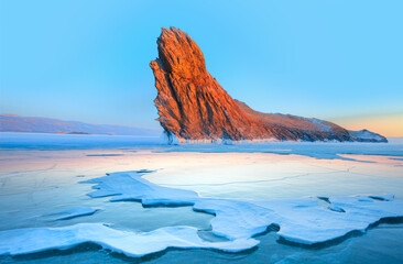 Beautiful winter landscape of frozen Lake Baikal at sunrise - A granite rock with steep slopes...