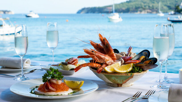 Luxurious seafood platter with champagne glasses and a stunning ocean view at a waterfront restaurant