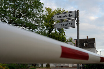 Signposts in Flensburg to judicial authorities and the theater, in front of a red and white barrier