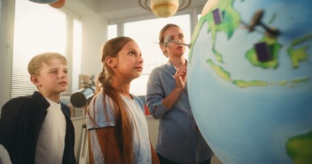 STEM Class: Elementary School Students Learning Renewable Energy Sources. Female Teacher Explaining...