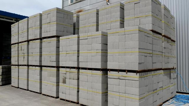 A neat stack of concrete blocks, secured with bright yellow tape, ideal for building and construction projects