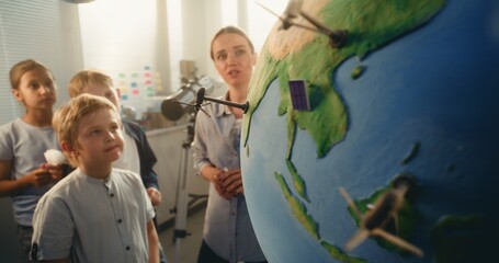Ecology STEM Class: Elementary School Boy Attaching Miniature Model of Wind Turbine to Globe....