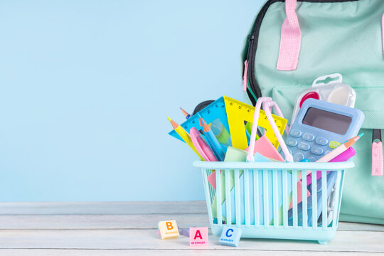 Back to school sale and shopping concept. Variety of school stationery in shopping basket pencils, paints, scissors, notebooks, calculator, school supplies, learning goods on colorful background 