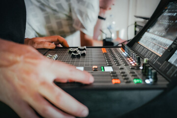 Two audiovisual engineers working together on a live event in a room. In the foreground, one of...